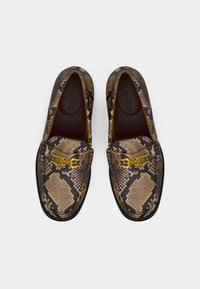 Paire de mocassins à motif écaille de serpent marron et noir avec détail en métal doré, marque ALDO à l'intérieur, semelles plates noires.