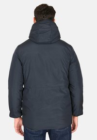 Giubbotto imbottito blu scuro con cappuccio, polsini elasticizzati e vita arricciata. Il materiale liscio ha una finitura opaca e un design minimalista.