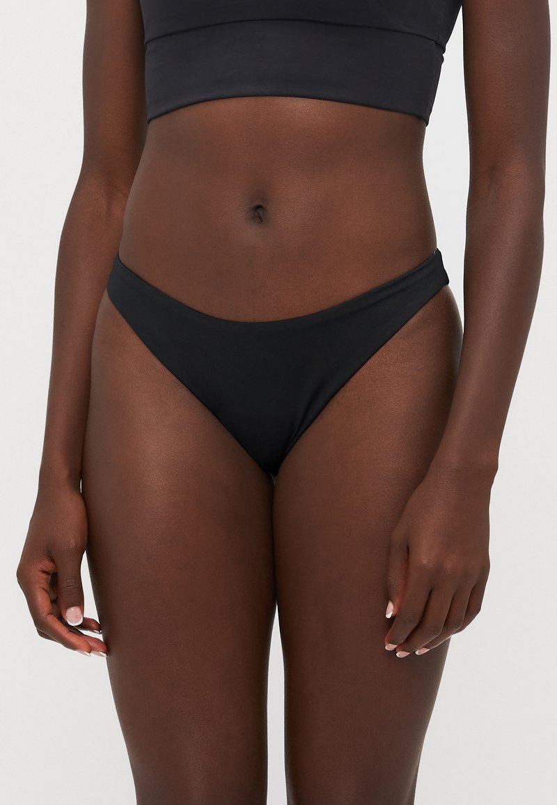 Sorte bikinibrie med sømløst design, laget av glatt stoff. Har lav midje, minimal dekning og ensfarget.
