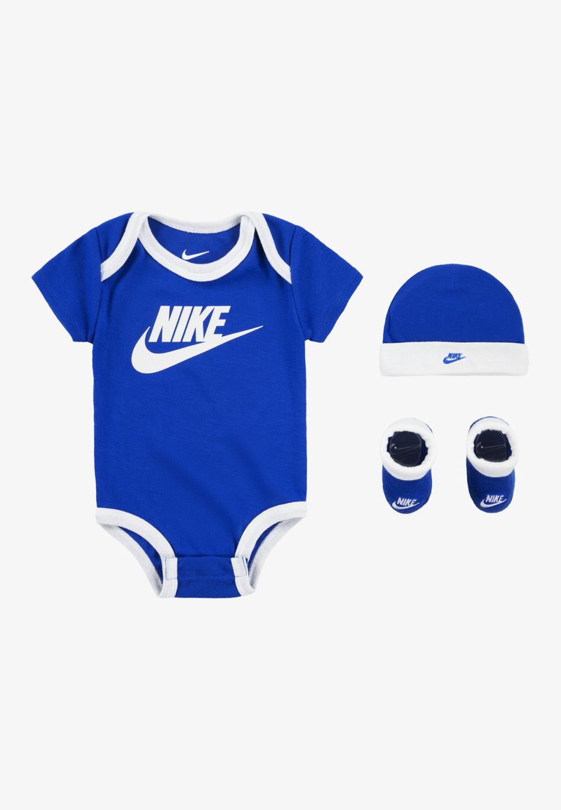 Kék pamut overál fehér díszítéssel és Nike logóval, kiegészítve egy ugyanolyan kék sapkával és Nike logós bébicipőkkel.