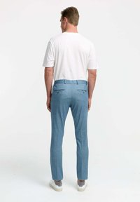 Light blue trousers with a tailored fit, featuring two back pockets, subtle texture, and flat front design, paired with a white shirt.