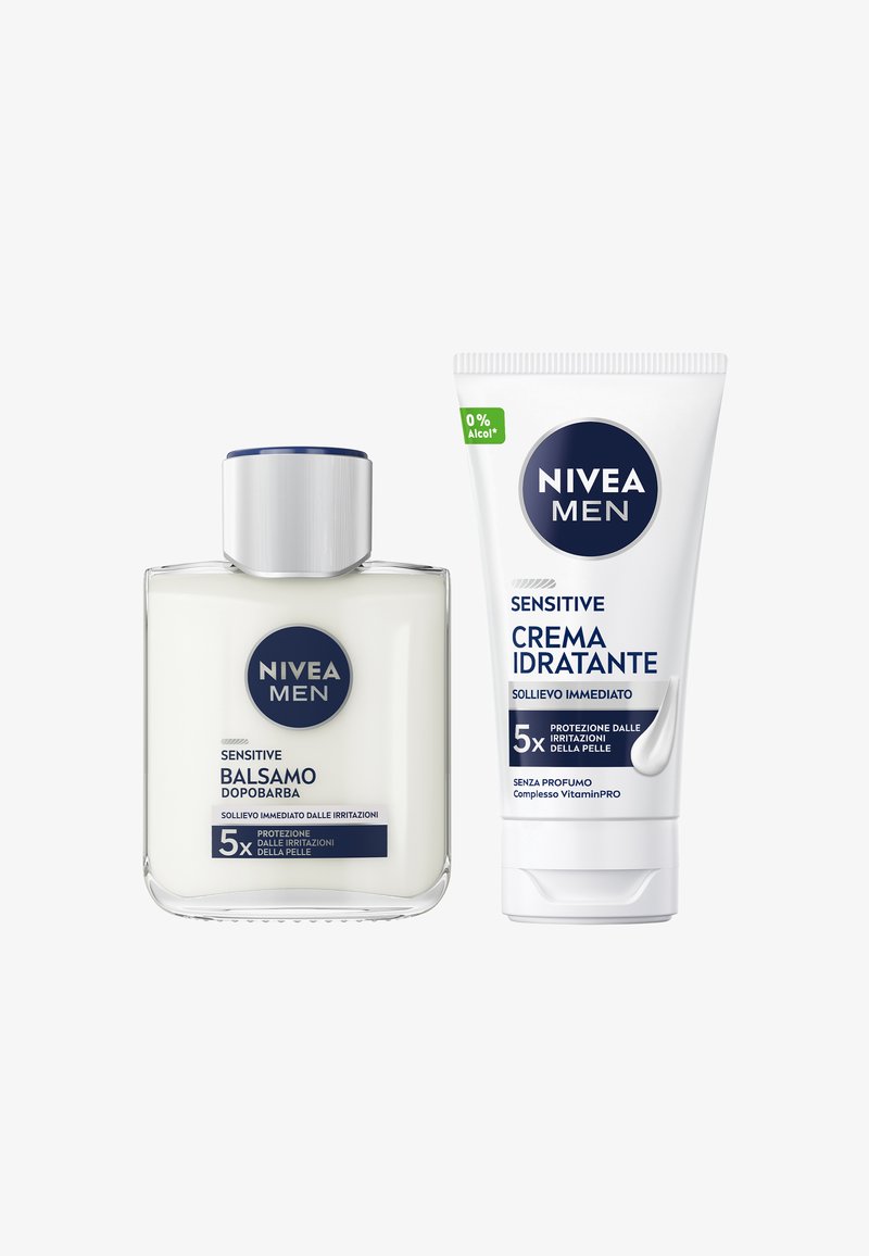 Balsamo Dopobarba NIVEA Men Sensitive in una bottiglia di vetro trasparente con un tappo argento, accanto a un tubo bianco di crema per il viso, entrambi con dettagli blu.