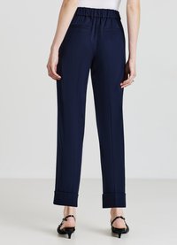 Pantaloni blu navy con fascia elastica arricciata in vita, tasche laterali, vestibilità sartoriale e orli con risvolto, realizzati in un tessuto liscio.