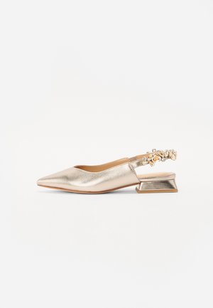 Metallic gold slingback shoe with pointed toe and block heel. Features embellished strap with clear and light-colored stones. Smooth texture.