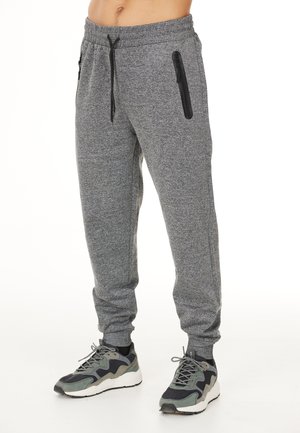 Gray joggers made of soft, textured fabric, featuring black zippered side pockets and an elastic waistband with a drawstring.