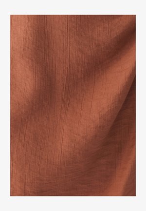 Tissu couleur rouille avec une surface texturée présentant de douces et fines rides. Le matériau semble léger et respirant.