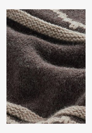 Dunkelbrauner Wollstoff mit einer fadenähnlichen Struktur, der entlang der Kante ein hellbeiges Band mit einem Strickmuster aufweist. Weicher und warmer Eindruck.