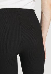 Svart ribbad leggings med hög midja, som har texturerad tyg och en tajt passform, vilket betonar en strömlinjeformad silhuett.