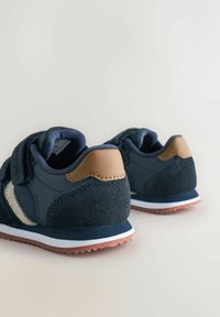 Pair of navy blue toddler sneakers with beige accents, velcro straps, and textured rubber soles on a light background.