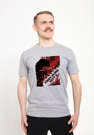 Grå bomulds T-shirt med et rødt og sort grafisk design af en figur med teksten "FIRST BLOOD PART II" i fed skrift.