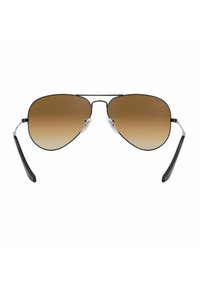 Occhiali da sole aviatori con lenti a sfumatura marrone, montatura nera metallica, cuscinetti per il naso trasparenti e punte delle stecche nere, caratterizzati da un design elegante e minimalista.