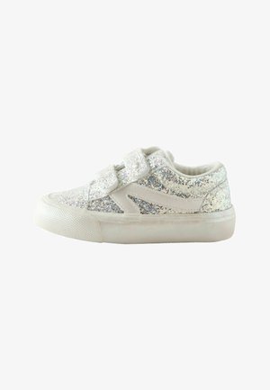 Børnestørrelse sneakers med hvidt glitrende stof, to velcrolukninger, hvid sål og lysebeige detaljer.