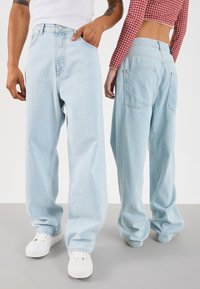 Ljusblå jeans med vida ben i denim, med hög midja, femficksdesign och subtil blekning. Matchas med vita sneakers.