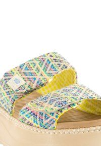 Sandalias slip-on tejidas con un patrón geométrico multicolor. Presentan acentos amarillos y una suela acolchada beige.