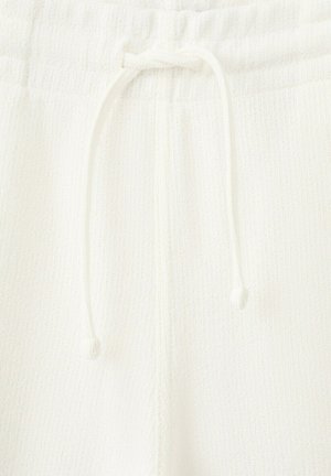 Pantalones de tela de punto blanca con cintura elástica y cordón ajustable atado en el centro delantero.