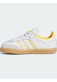 Weißer Sportschuh mit gelben Akzenten, drei weißen Streifen, strukturiertem Leder, Wildleder-Zehenkappe und Gummisohle. Schnürdesign.