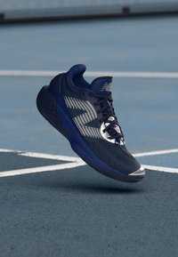 Dunkelblaue Sportschuhe mit texturiertem Obermaterial, silbernen Akzenten und schwarzen Schnürsenkeln. Verfügt über eine gepolsterte Sohle und ein rundes Zehen-Design.
