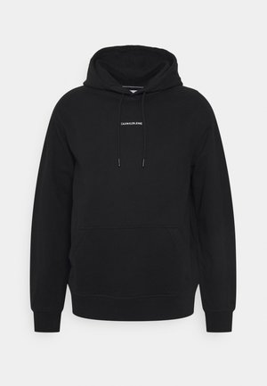 Sweat à capuche noir avec poche avant, cordons et petit logo blanc "Calvin Klein Jeans" sur la poitrine.