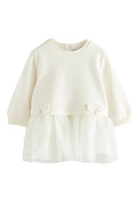 cremefarbenes Sweatshirt mit Tüllüberzug, versehen mit zwei kleinen Schleifen an der Taillenlinie. Weicher Stoff und runder Ausschnitt. Lange Ärmel.