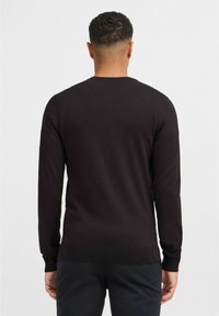 Pulover tricotat negru cu mâneci lungi și decolteu rotund, având mâneci și tiv cu nervuri. Textură netedă, design ajustat, vedere din spate.