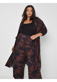 Lässiges, navy-blaues Outfit mit abstrakten Mustern in Orange und Blau. Weicher Stoff mit einer Kimono-artigen Jacke und hochgeschnittenen Hosen.