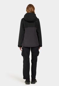 Black jacket with a hood, color-blocked gray lower section, and elastic cuffs, paired with black cargo pants featuring side pockets.