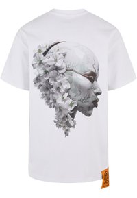 Hvit bomull T-skjorte med et detaljert grafisk bilde av et ansikt med blomster og geometriske mønstre i grå og lysegrønne toner på baksiden.