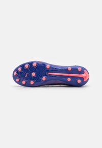 Voetbalschoen met een paarse kunststof zool voorzien van 12 roze noppen, een gestructureerd oppervlak en een slank ontwerp met een gestileerd logo-accent.