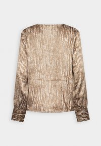 Blouse beige à manches longues avec un motif à rayures verticales blanches irrégulières, poignets boutonnés et encolure ronde, vue de dos.