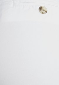 Tissu en denim blanc avec un détail de bouton visible, présentant une texture lisse et un motif de tissage diagonal. Design épuré et minimaliste.