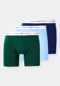 Dreiert-Pack Boxershorts in Grün, Hellblau und Marineblau. Jede Shorts hat einen weißen Bund mit dem Logo "TOMMY HILFIGER" oben. Aus Baumwolle.