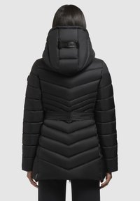 Sort puffjakke med en chevron-design og en stor hætte. Har en bælte i taljen og lynlåse ved kanten. Tekstureret, isoleret materiale.