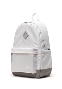 Sac à dos en tissu gris avec un motif en forme de losange, une poche avant, et un fond gris foncé contrasté. Il est doté d'une poignée sur le dessus et d'un écusson logo.