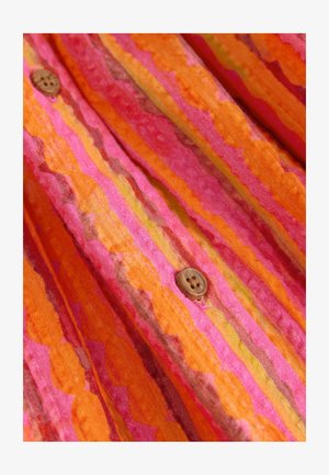 Tela multicolor con rayas onduladas en naranja, rosa y amarillo, con un detalle de botón de madera en el lado derecho.