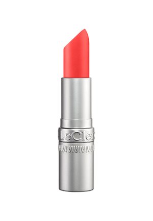 Heller Korallenroter Lippenstift in einer silbernen Metallhülse mit eingeprägtem Markennamen am Boden, aufrecht stehend vor weißem Hintergrund gezeigt.