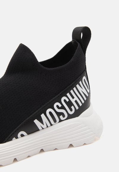 Μαύρο sneakers χωρίς κορδόνια με λευκή παχιά σόλα και έντονο λευκό λογότυπο MOSCHINO στην πλαϊνή επιφάνεια.