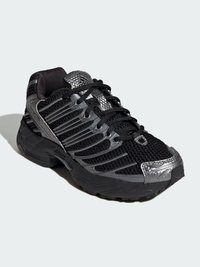 Čierna športová obuv s vrchnou časťou z sieťoviny so striebornými akcentmi, textúrovanými detailmi a pevnou gumovou podrážkou. Dizajn so šnúrkami pre bezpečné upevnenie.