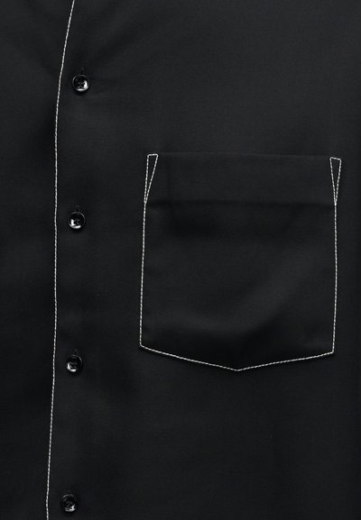 Μαύρο πουκάμισο με κουμπιά στο μπροστινό μέρος και τσέπη στο στήθος περιγραμμένη με λευκή αντίθεση ραφής.