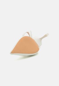 Hvit høyhælt sko med spiss tupp og en teksturert brun såle. Har en slank design med en minimalistisk stropp. Glatt lærfinish.