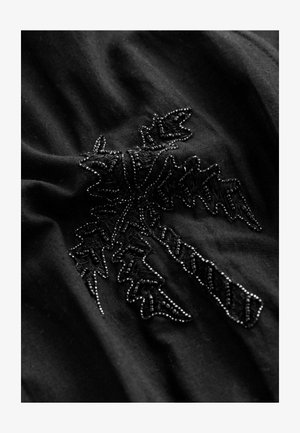 Țesătură neagră cu broderie complicată de culoare neagră în model de frunze, însoțită de mici accente cu mărgele. Apărarea moale și texturată.