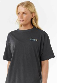 T-shirt in cotone grigio scuro con colletto rotondo e maniche corte. Presenta un piccolo logo "RIPCURL" multicolore sul petto.