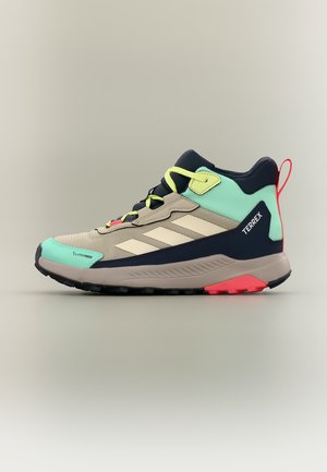 Chaussure de randonnée montante Adidas Terrex beige, noire, turquoise et rouge avec des lacets jaunes et une semelle robuste, vue de côté.