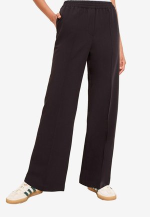 Zwarte wijde broek gemaakt van zachte stof, met een elastische tailleband, zijzakken en een gladde, onverwerkte oppervlakten.