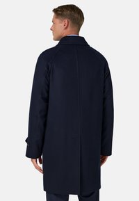 Mornarsko volna plašč s ravnim krojem, dolgimi rokavi in zarezanim ovratnikom. Ima gladko teksturo in minimalističen dizajn.