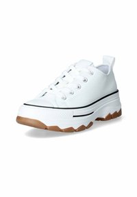 Zapatilla de lona blanca con suela de goma gruesa color caramelo, detalle de franjas negras, punta redonda y diseño de cordones. Presenta una lengüeta en el talón para facilitar su colocación.