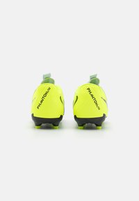 Neon žlté futbalové kopačky s textúrovaným povrchom, sivými akcentmi a čiernymi podrážkami. Na bokoch a na pätnej časti sú umiestnené písmená značky pre jednoduché obúvanie.