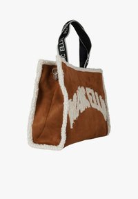 Brown suede tote bag with cream sherpa trim, featuring a black branded handle and contrasting lettering on the front side.