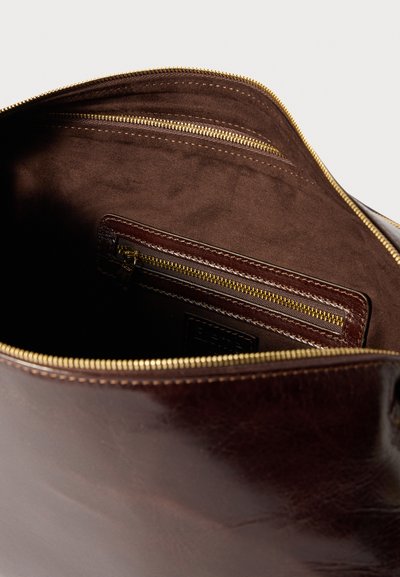 Brown leather bag interior featuring a soft brown texture, gold hardware zippers, and a compact zippered pocket.