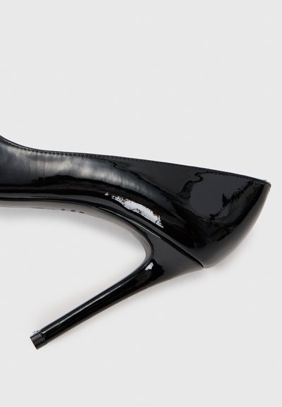 Chaussure à talon haut en cuir verni noir avec un bout pointu, un design élégant et un talon aiguille fin. Texture lisse avec une finition brillante.