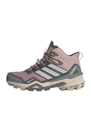 Lila-grauer Adidas Terrex Wanderschuh mit Gore-Tex, dicker Profilsohle und reflektierendem Drei-Streifen-Logo an der Seite.